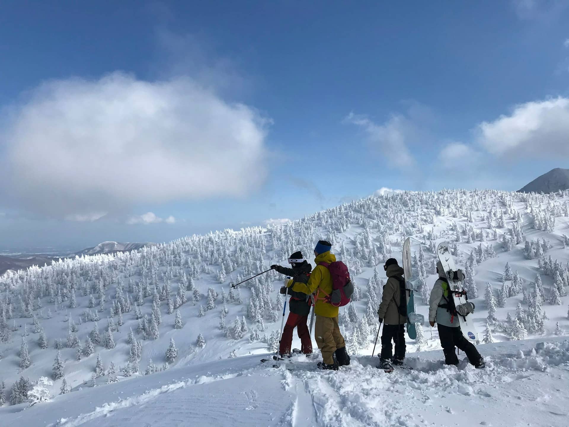 Four skiers and snowboarders standing on a snowy ridge above frost-covered trees, a mountain beyond, Deschutes Riverfront Retreat near Sunriver, Oregon