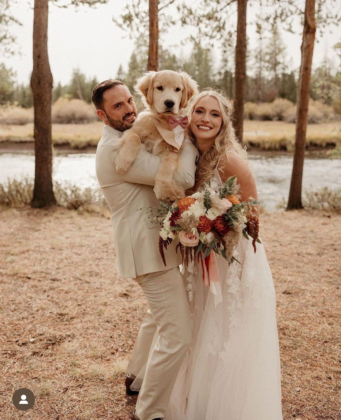 A newly married couple holding a golden retriever puppy between them, the river behind, Deschutes Riverfront Retreat near Sunriver, Oregon